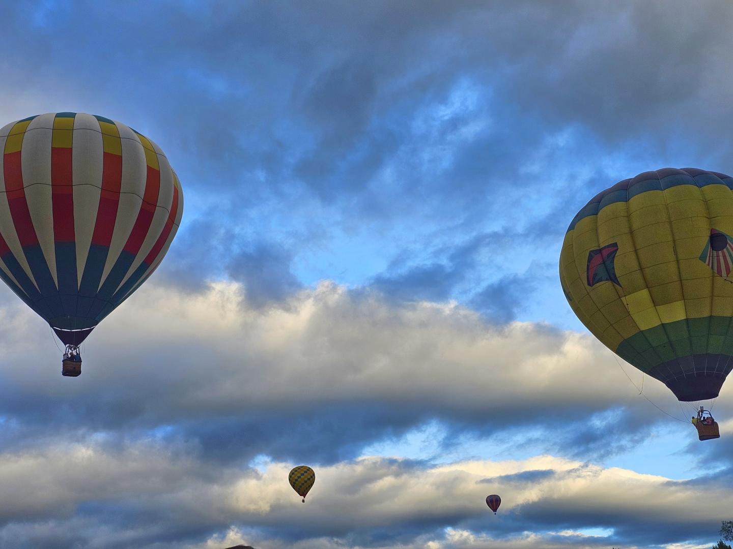 Hot air balloons in a cloudy sky, one striped and one yellow.