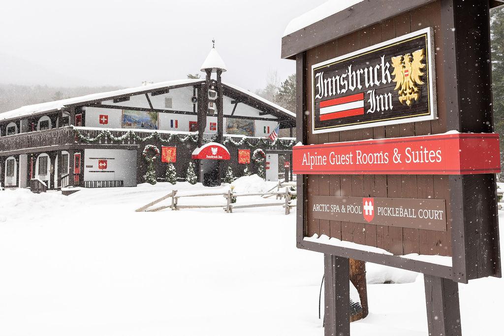 Snow-covered chalet-style building with festive decorations and a prominent sign in the foreground.