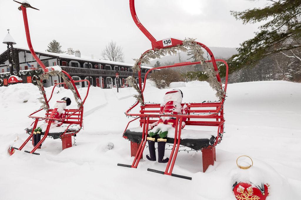 Red ski lift chairs with snowman figures in a snowy landscape.