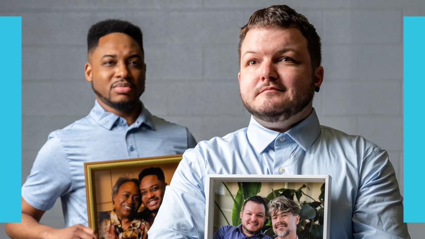 Two men in blue shirts holding framed photos of same-sex couples.