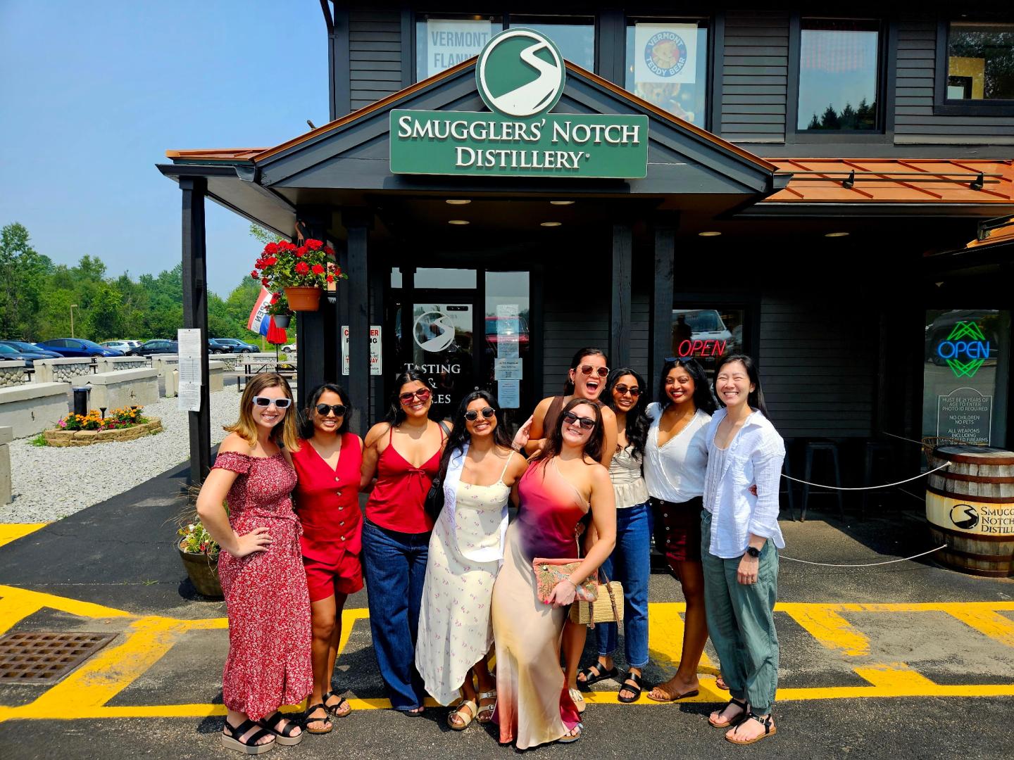 Group posing happily outside a distillery under a sunny sky.