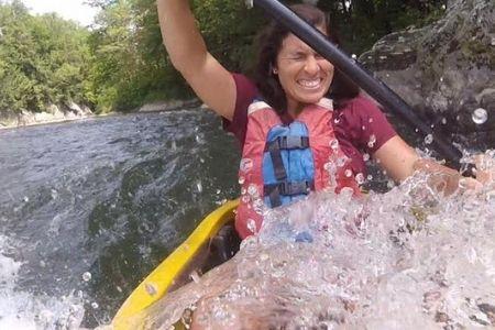 Woman kayaking energetically through rapids.