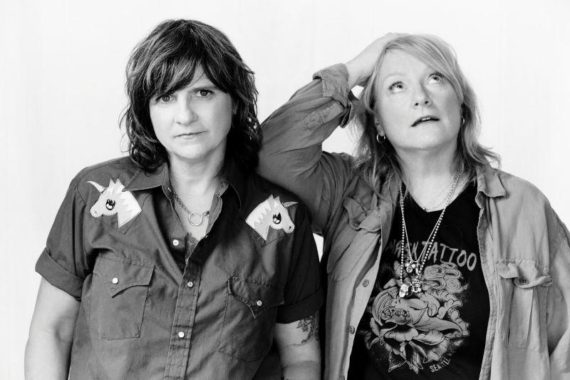 Two women in black and white, one looking at camera, other gazing upwards.