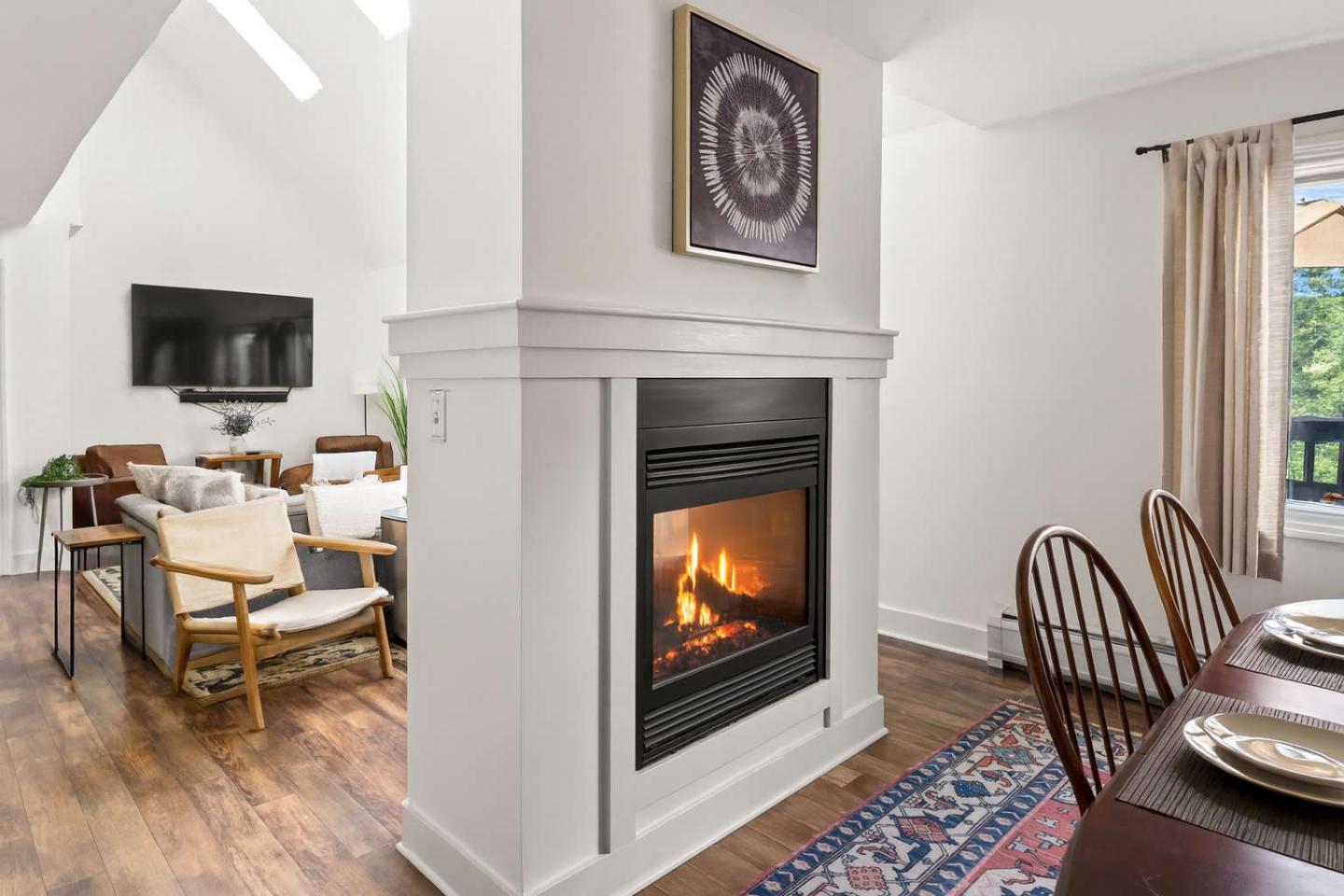 Cozy living room with a fireplace, wooden chairs, and a dining table.