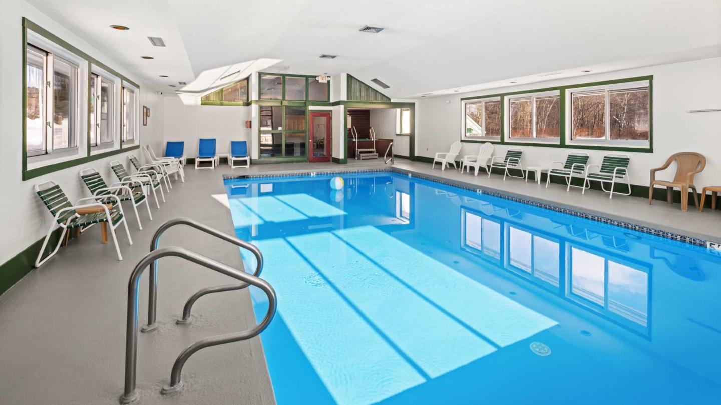 Indoor pool with chairs and large windows. Bright and spacious.
