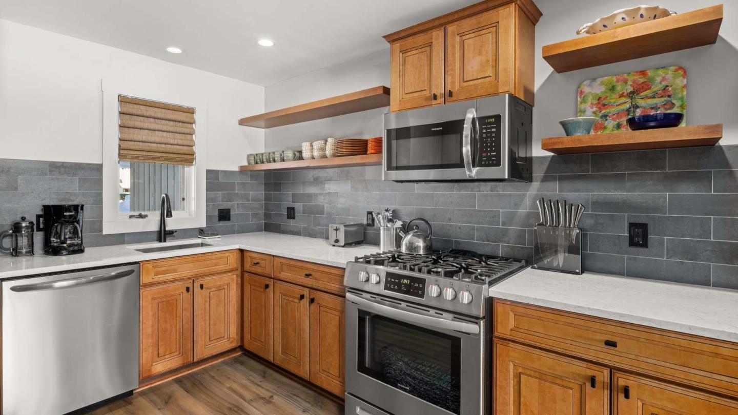 Modern kitchen with wooden cabinets, stainless steel appliances, and gray tile backsplash.
