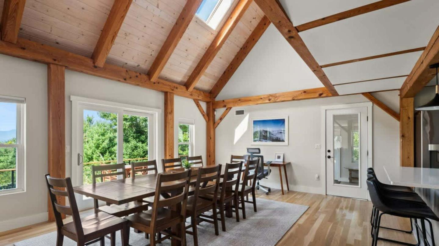 Spacious dining room with wooden beams, large table, and bright windows.