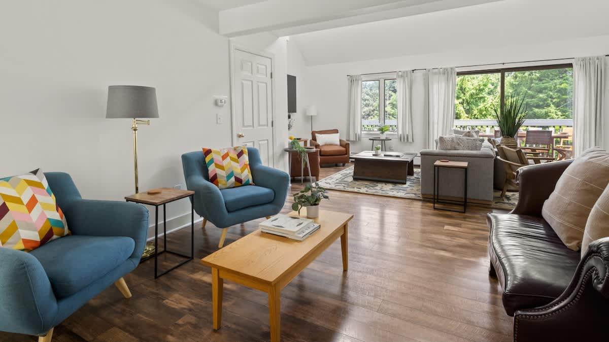 Spacious living room with blue chairs, a dark sofa, and a coffee table on wooden floor.