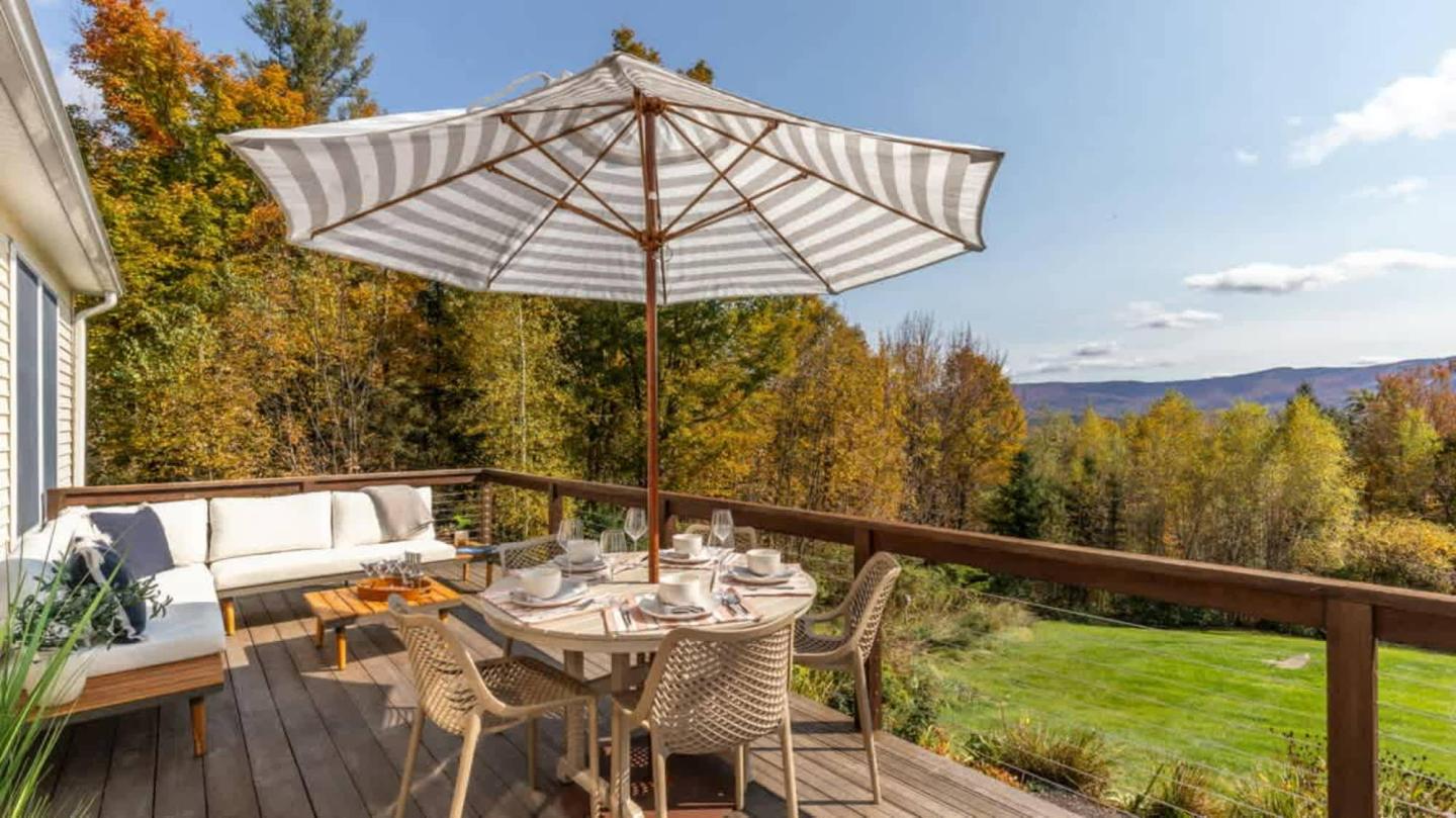 Sunny patio with table set for dining, surrounded by autumn foliage.
