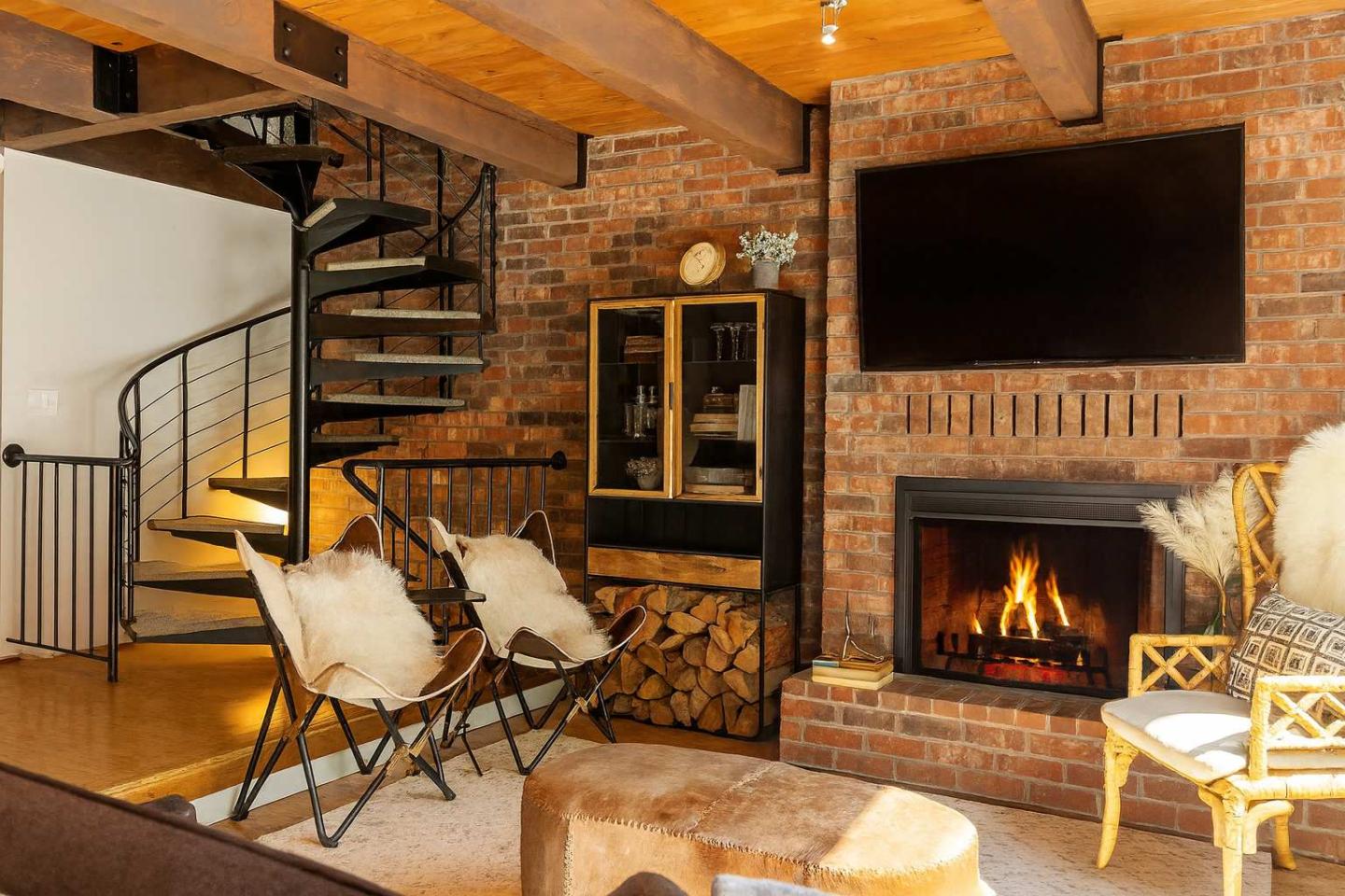 Cozy living room with fireplace, spiral staircase, and modern furniture.