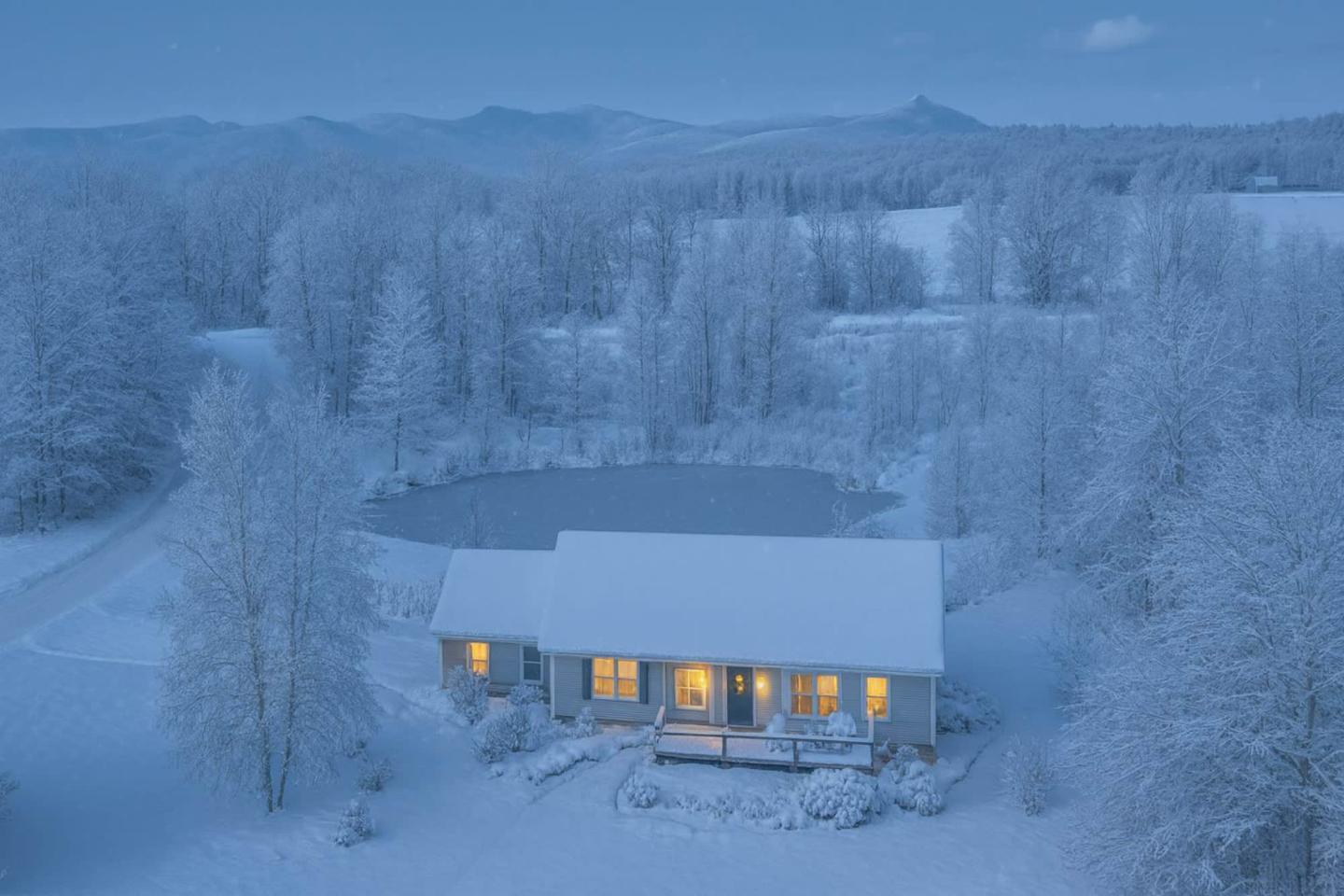 Snow-covered house with glowing windows in a winter landscape.