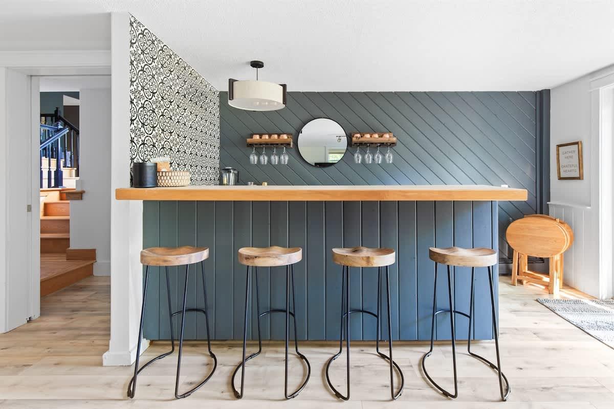 Stylish home bar with four stools and a circular mirror.