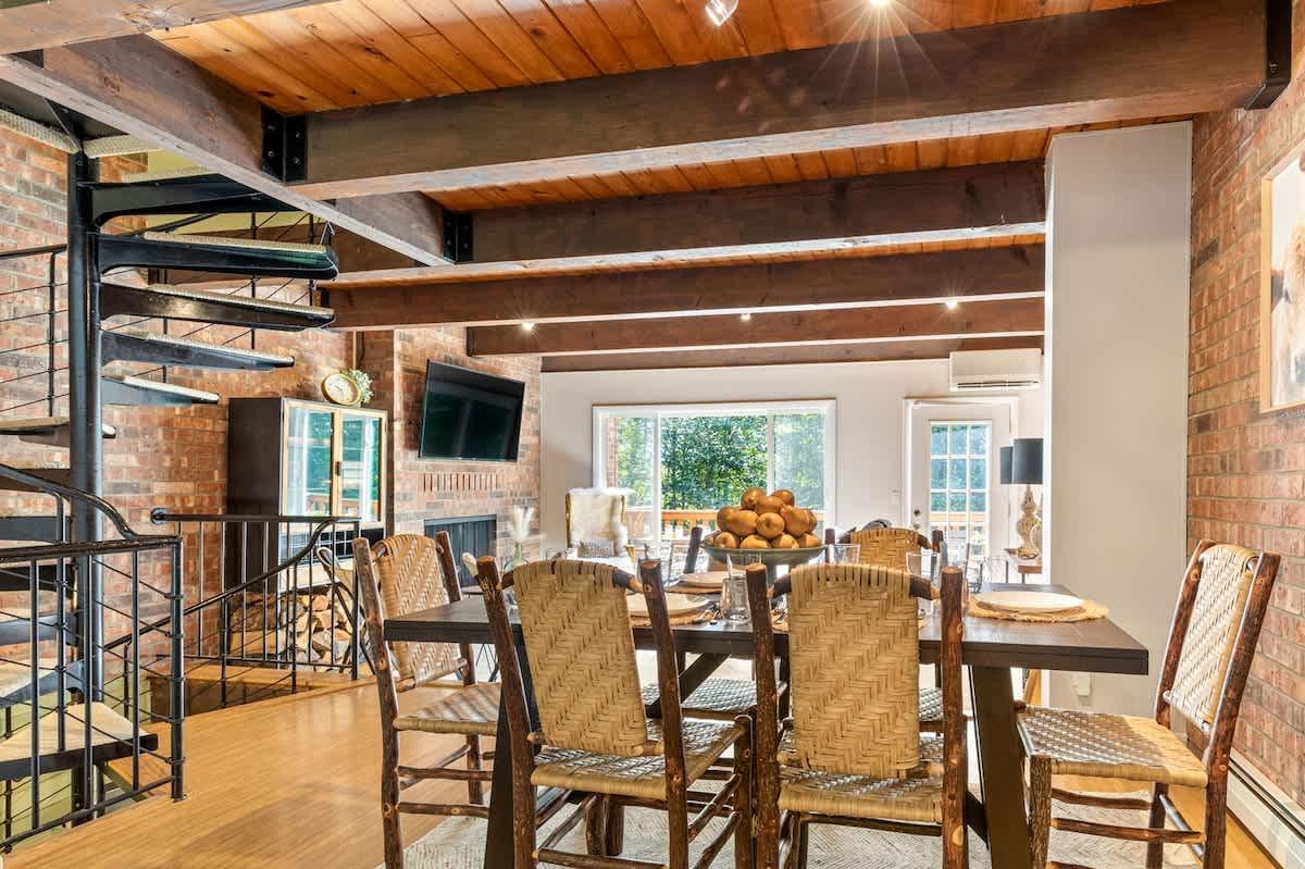Dining room with wooden beams, brick walls, and a table set for a meal.