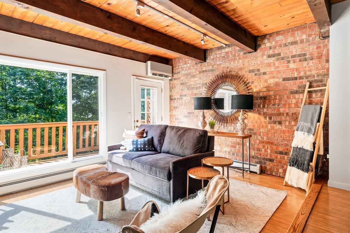 Cozy living room with brick wall, large window, and wooden beams.