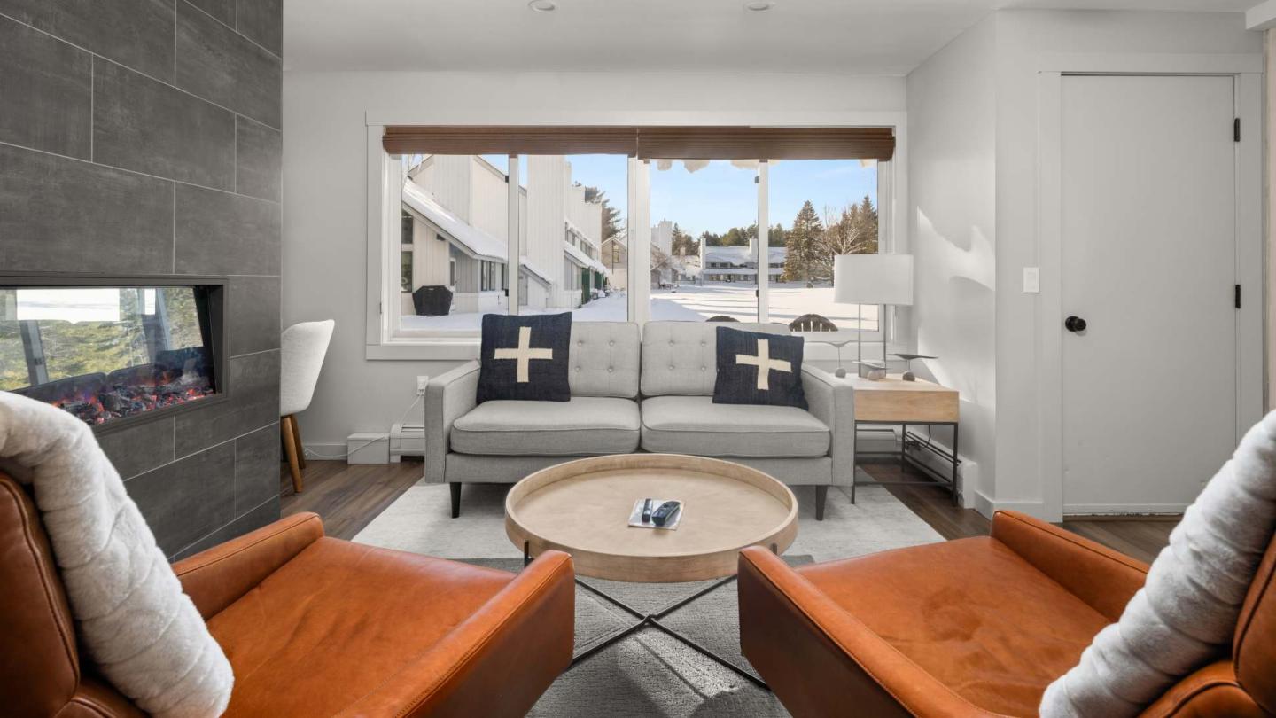 Cozy living room with orange chairs, gray sofa, and round table.