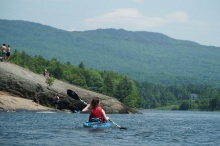 Kayaker paddling on a lake, surrounded by lush green hills.