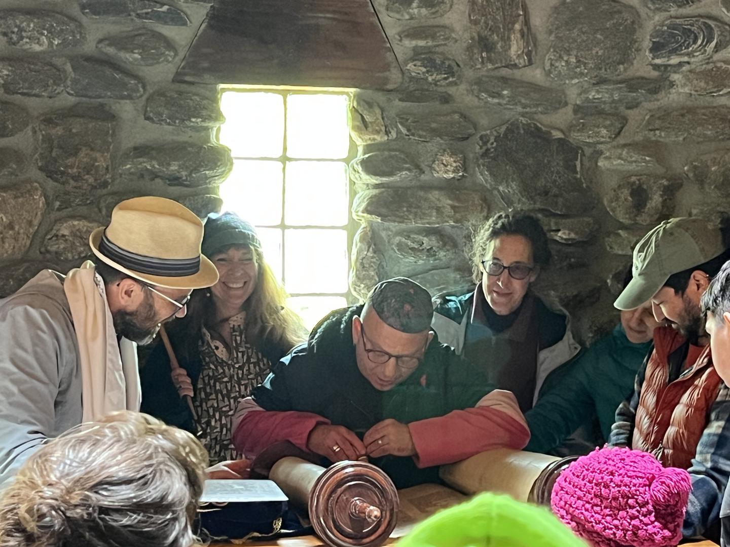 People gathered around a scroll in a dimly lit stone room.