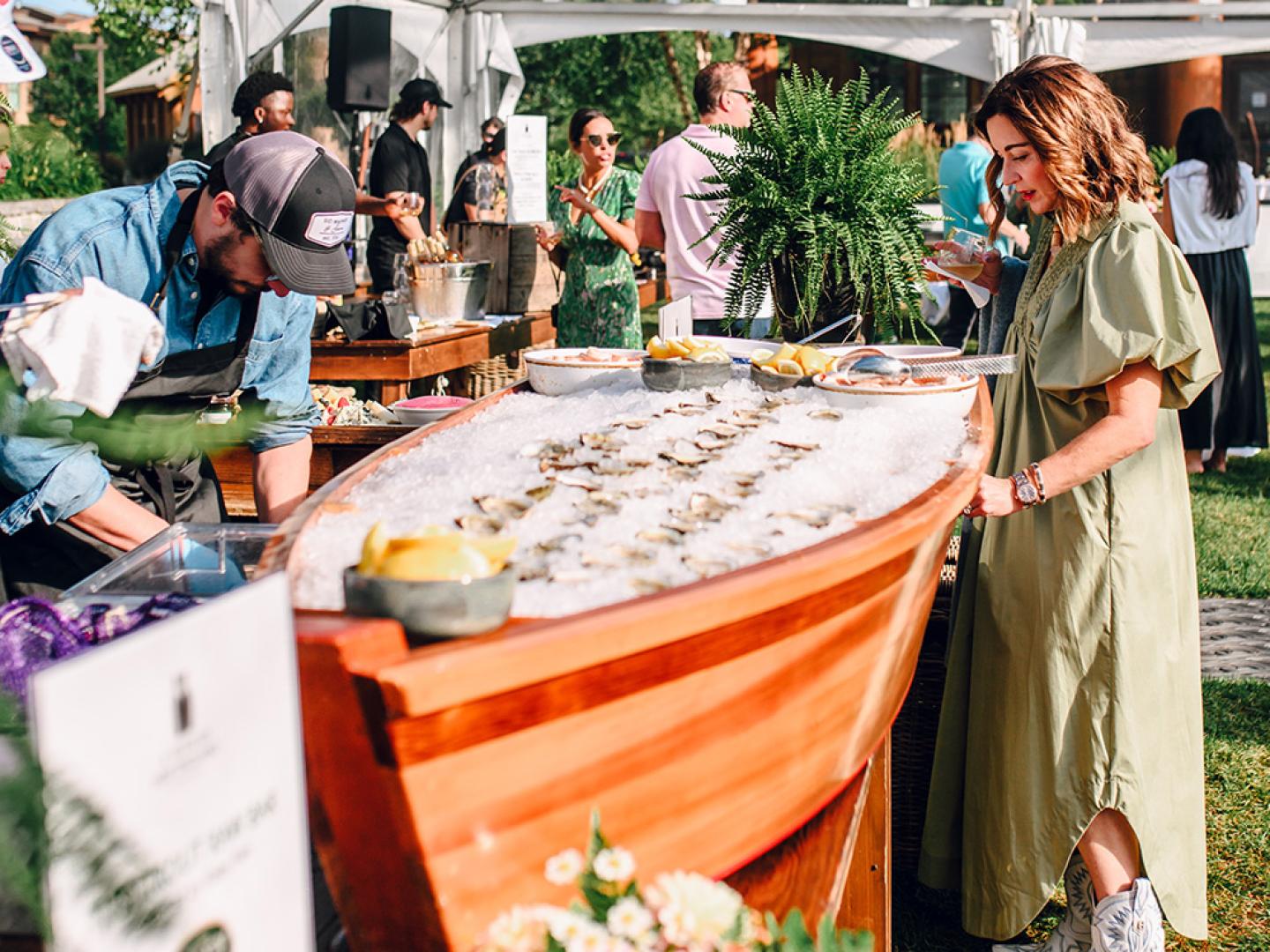 Outdoor event with people around a seafood ice display in a wooden boat.