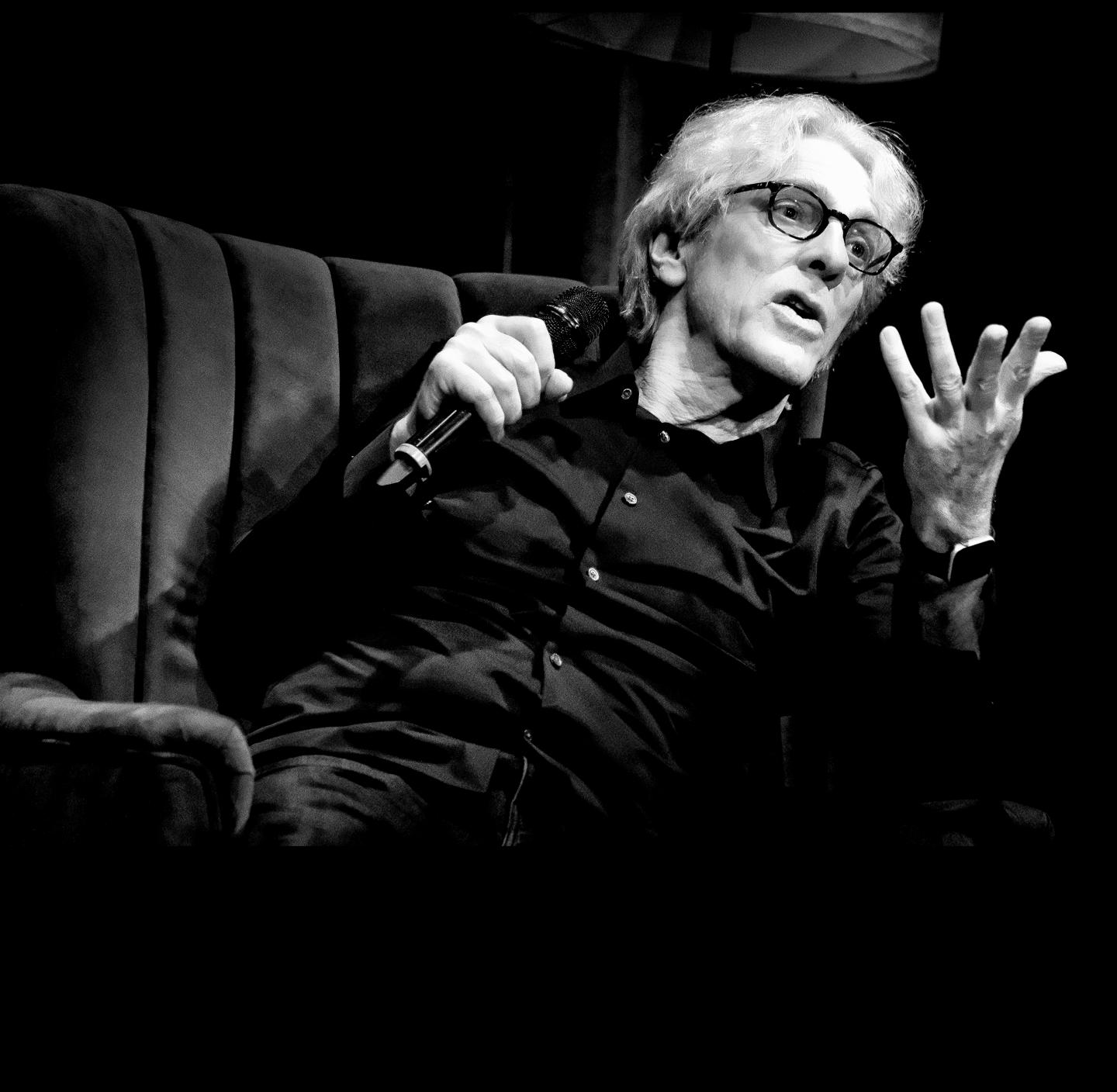 Man speaking passionately on a stage, monochrome photo.
