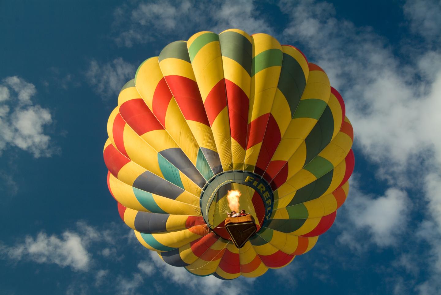 Colorful hot air balloon against a blue sky with clouds.