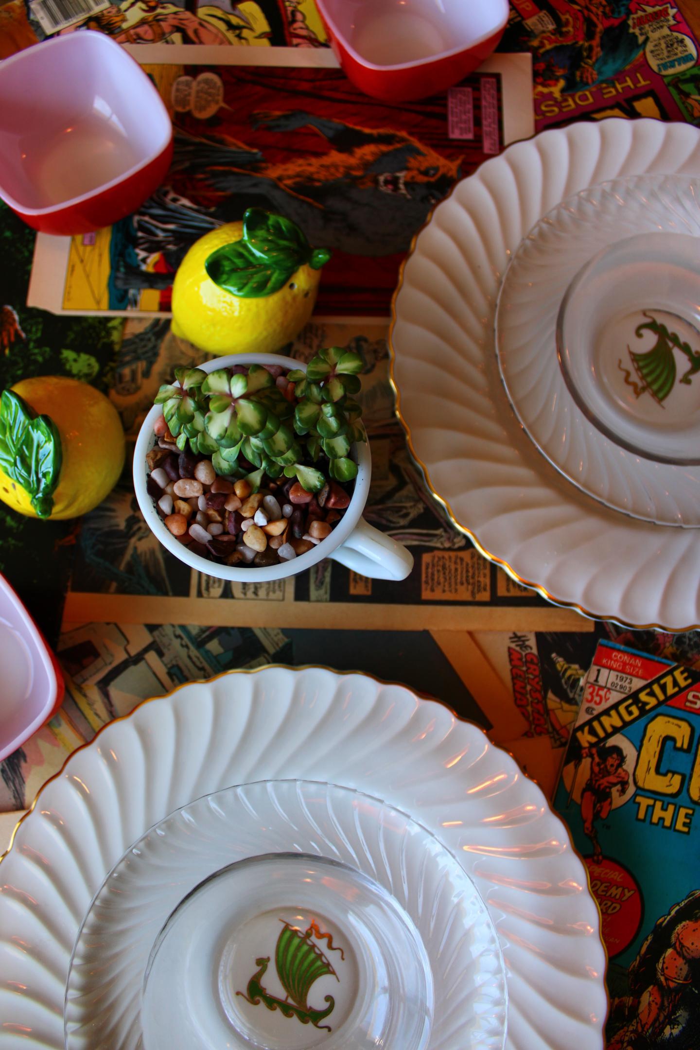 White plates on a comic-themed table with lemons and a bowl of beans.