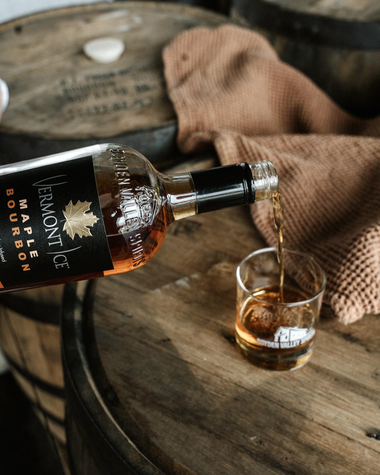 Pouring whiskey into a glass on a wooden barrel.