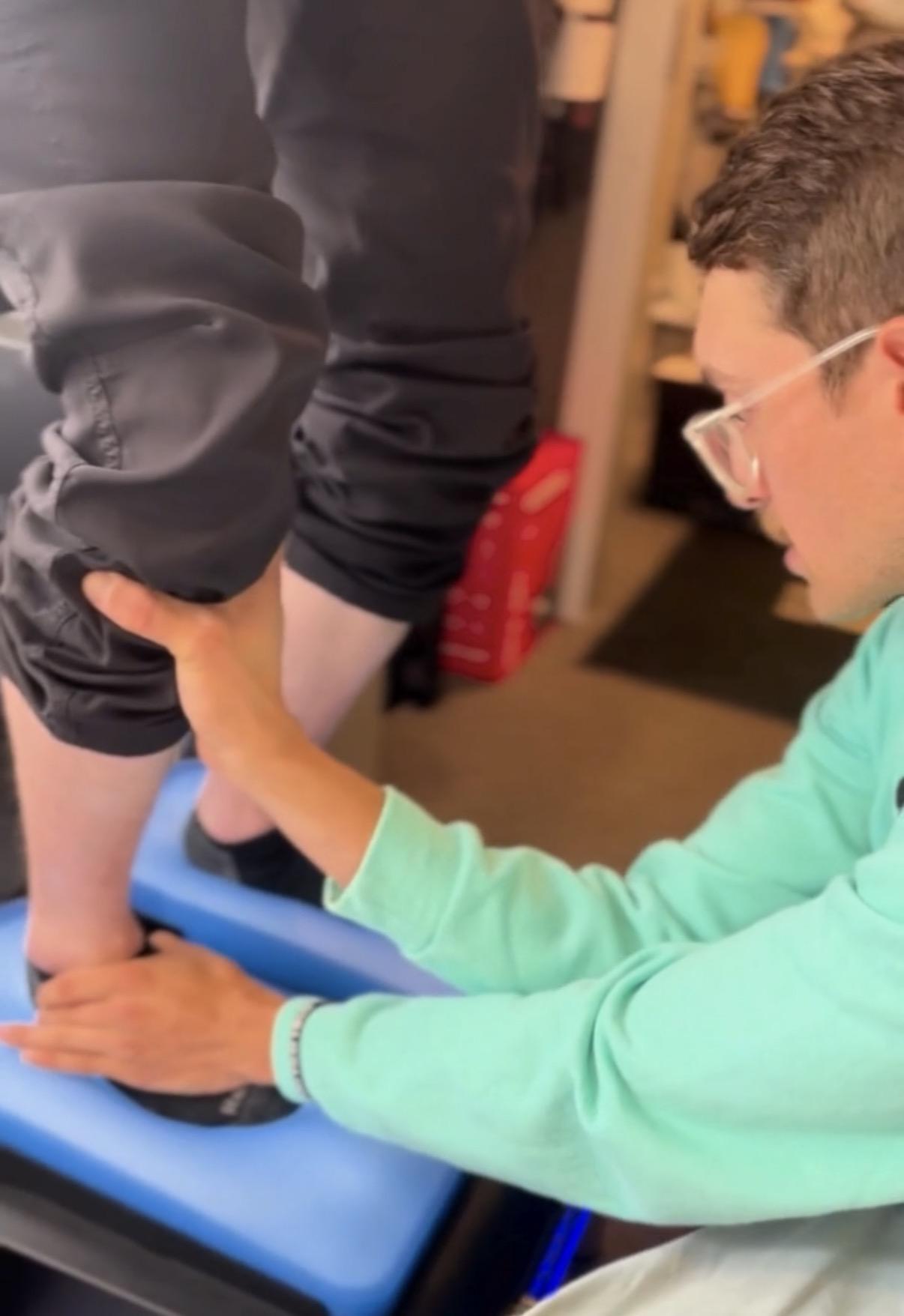 Person assisting another's leg on a blue platform.