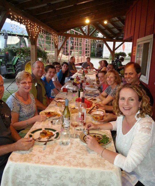 Family dining outdoors under a lit gazebo, sharing a meal at a long table.