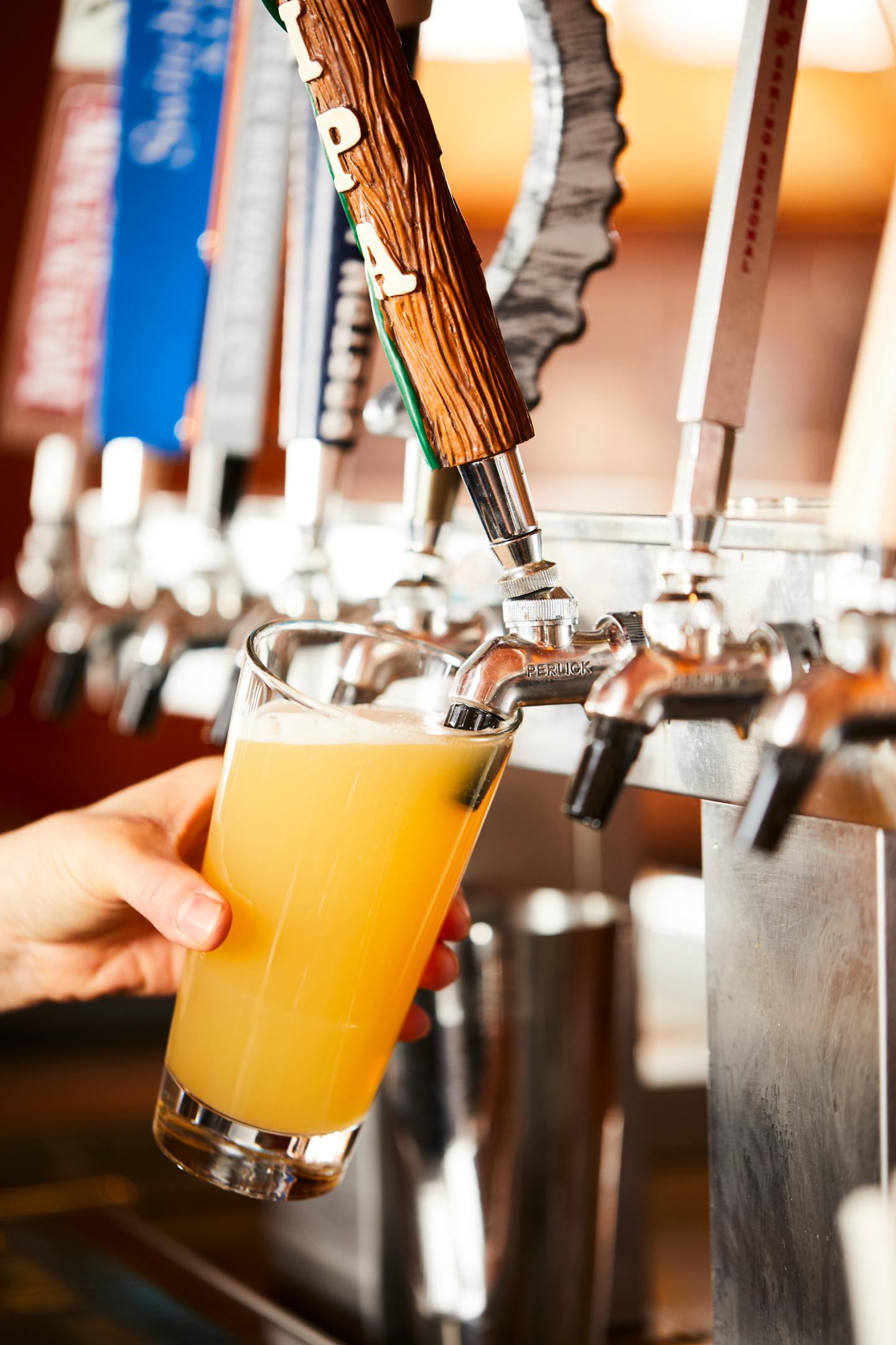 Draft beer being poured into a pint glass from a tap.