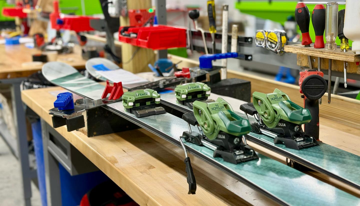 Ski on a workbench with green bindings, surrounded by tools and colorful accents.