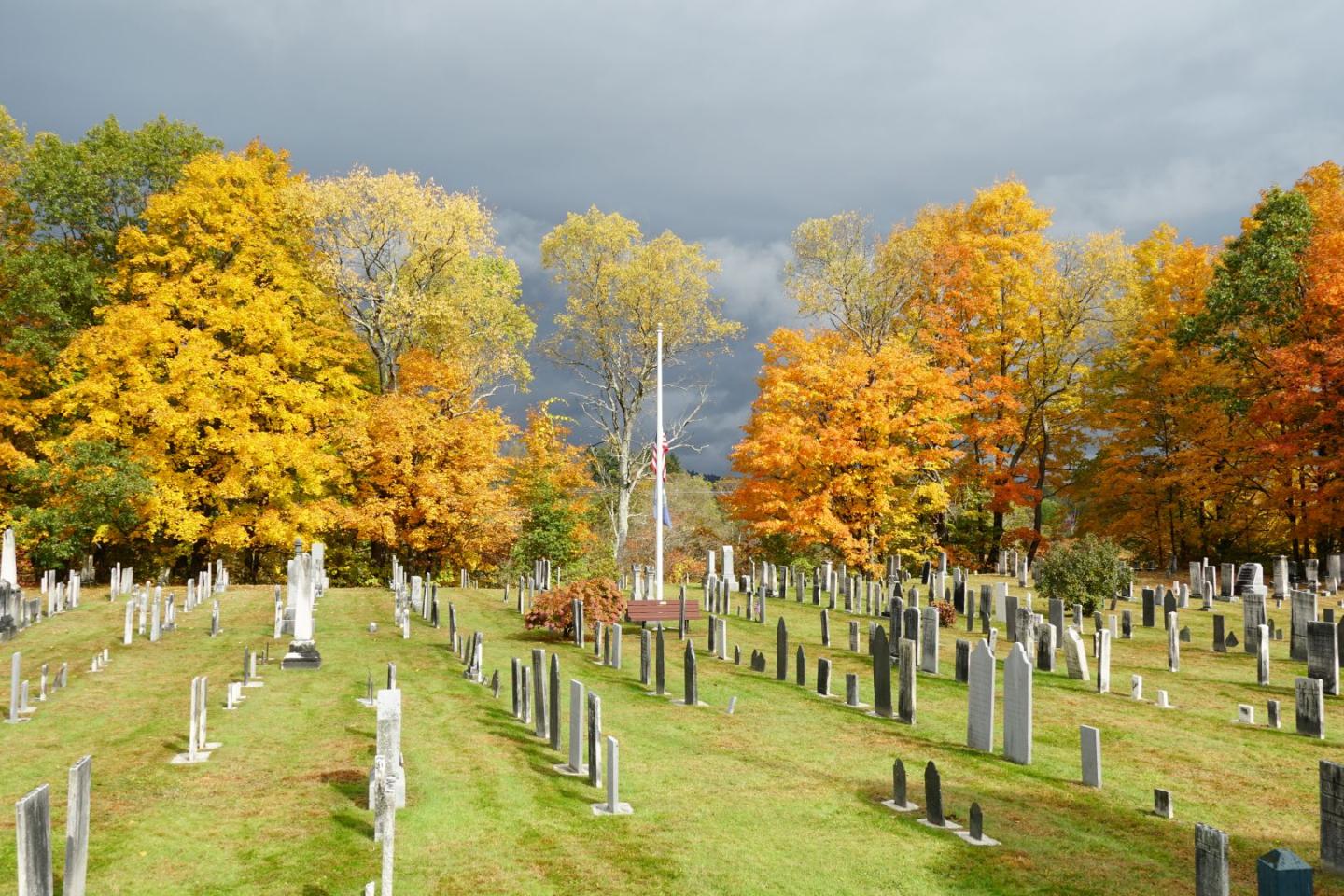 Cemetery with colorful autumn trees under a cloudy sky