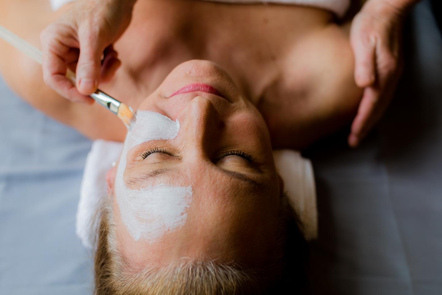 Woman receiving a facial mask treatment at a spa.