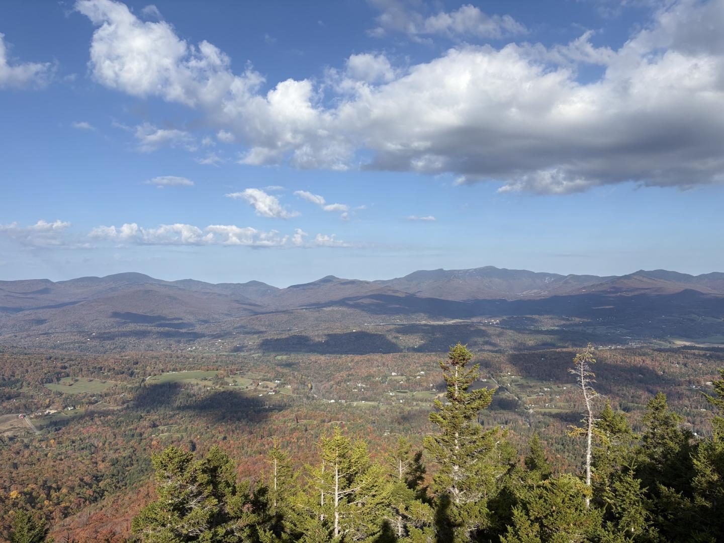 Mountain valley landscape under a blue sky with scattered clouds.