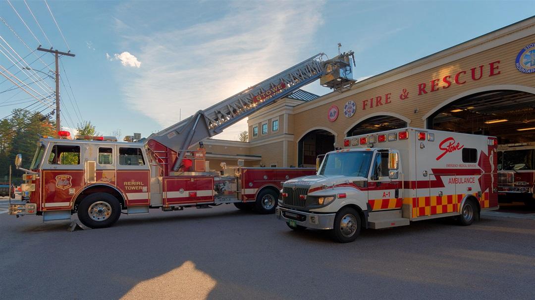 Fire truck and ambulance parked outside a fire station.
