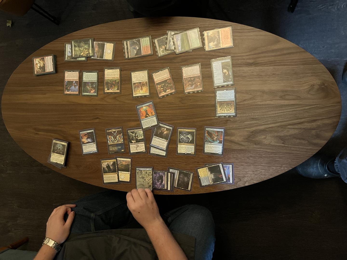 Overhead view of two people arranging cards on a round wooden table.