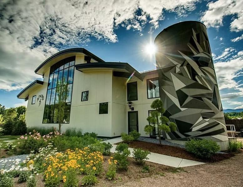 Modern white house with a striking geometric black-and-white facade under dramatic clouds.