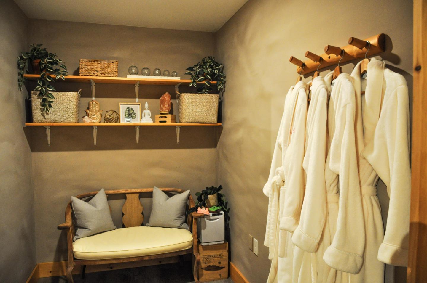 Cozy dressing room with robes on a wooden rack and shelves of decor.